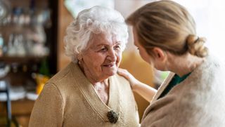 Younger person reassuring older person with hand on shoulder