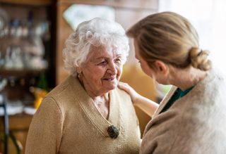 Younger person reassuring older person with hand on shoulder