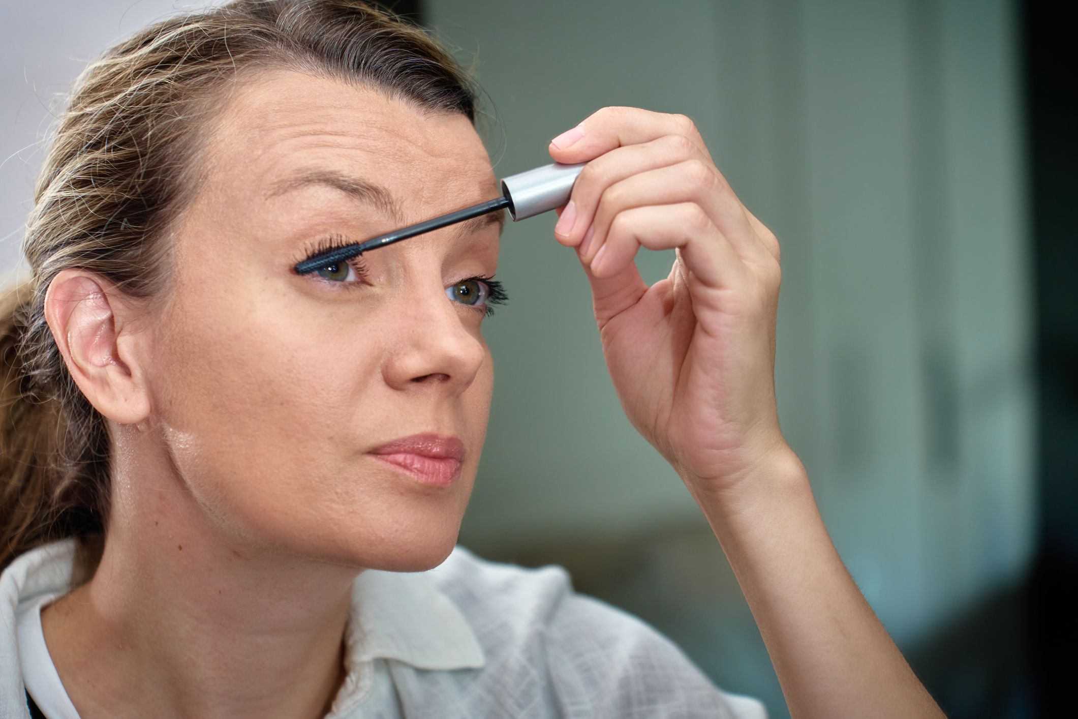 A woman applies mascara
