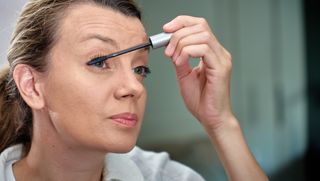A woman applies mascara