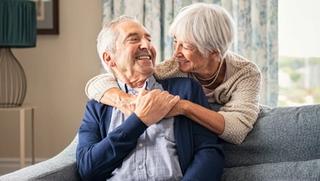 Older couple embracing over the back of a couch