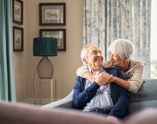 Older couple embracing over the back of a couch