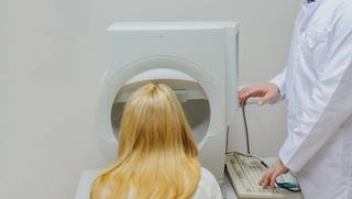 An eye care professional using a machine to conduct a visual field test.