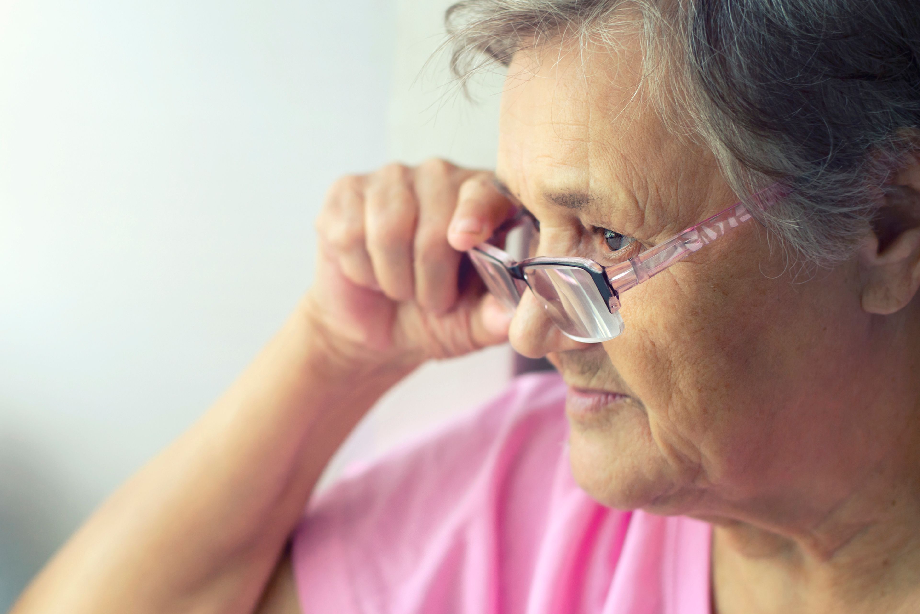Older person adjusting glasses