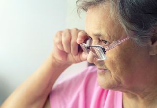Older person adjusting glasses