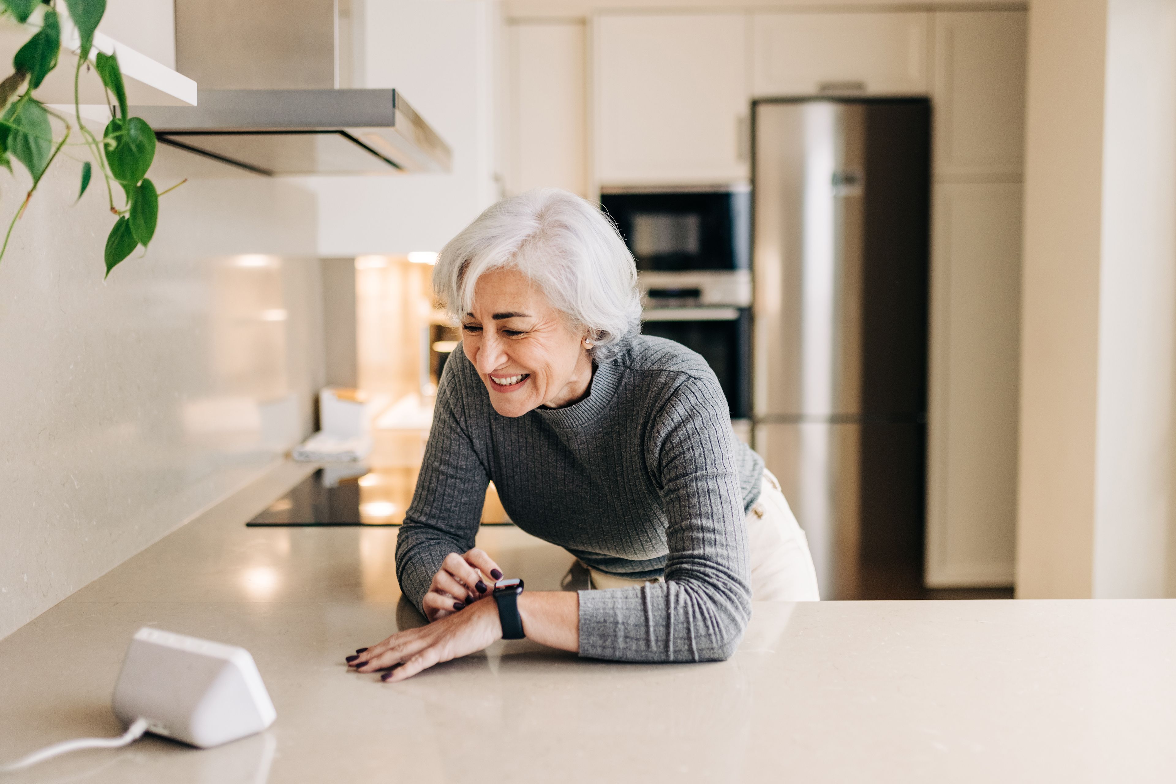 Older person using speech activated virtual assistant in kitchen