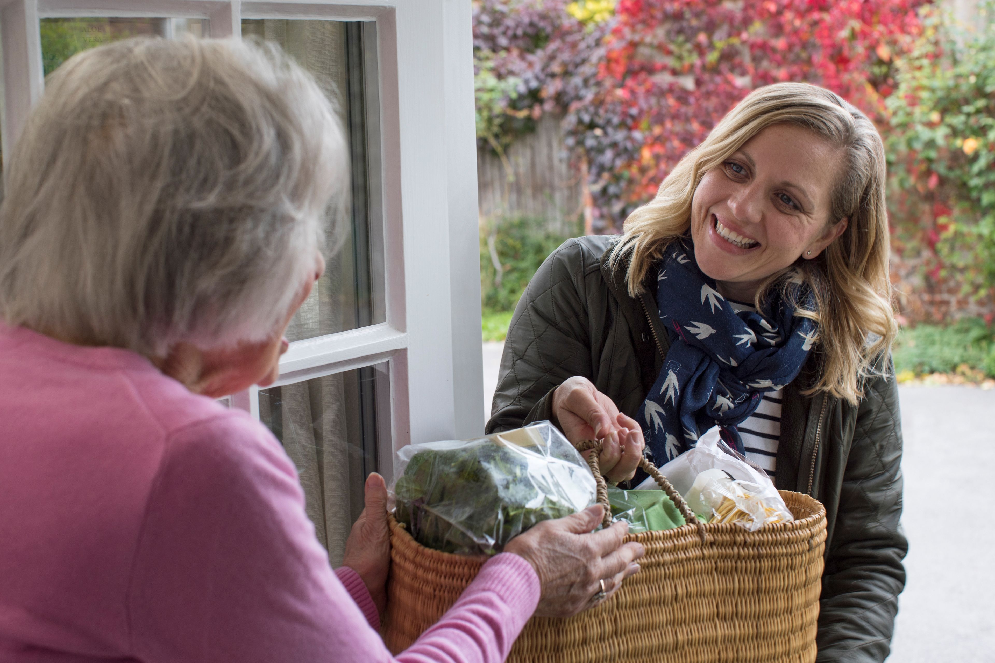 Carer delivering groceries to older person