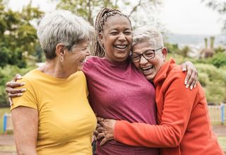 Group of three older people hugging outdoors