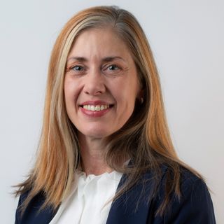 A smiling woman standing in front of a white background
