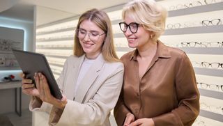 Eye care professional showing tablet to client in store
