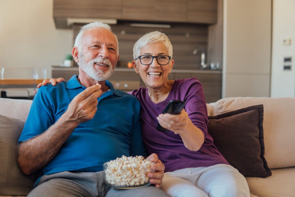 Older couple watching TV together while eating popcorn