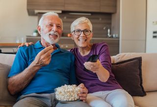 Older couple watching TV together while eating popcorn
