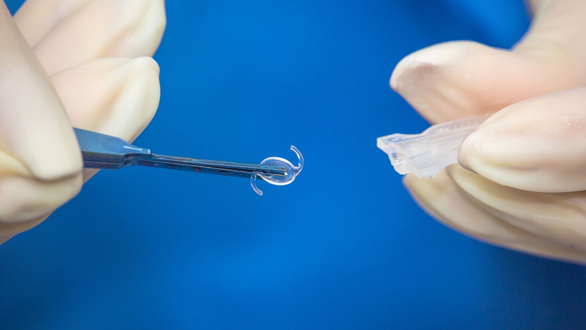 A close-up of a surgeon holding an IOL