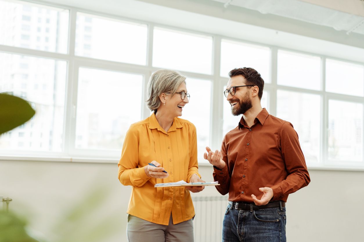 Older person smiling and laughing with younger coworker