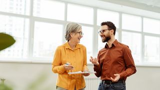 Older person smiling and laughing with younger coworker