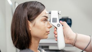 A woman having her intraocular pressure checked by an eye care professional.