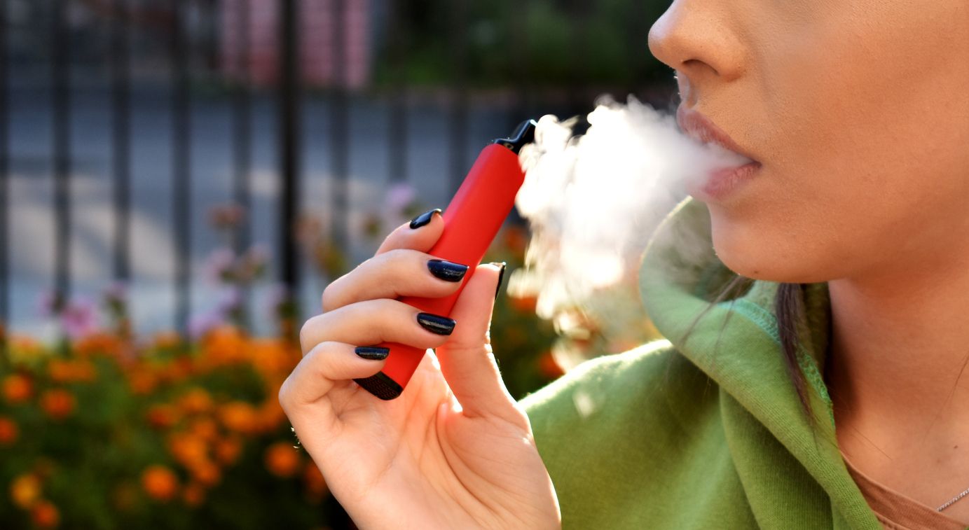 Person vaping with a close up on their hand and mouth