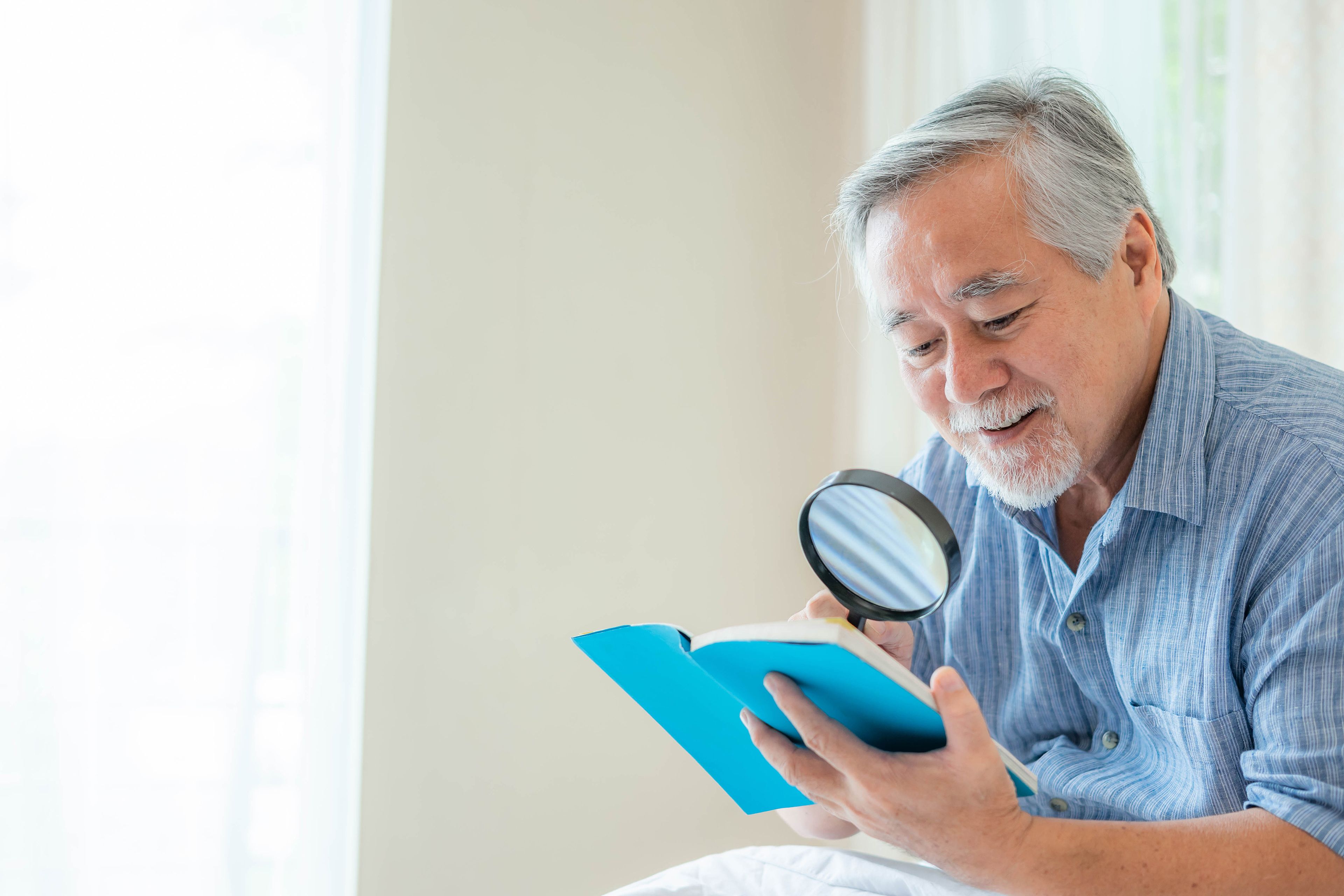 Older person using magnifying glass to read book