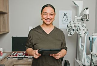 Smiling optometrist holding an iPad in her office