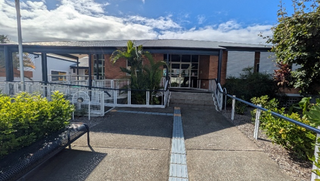 The exterior of the Queensland Blind Association Building, with two pathways leading to the entrance, one with stairs and one ramp.