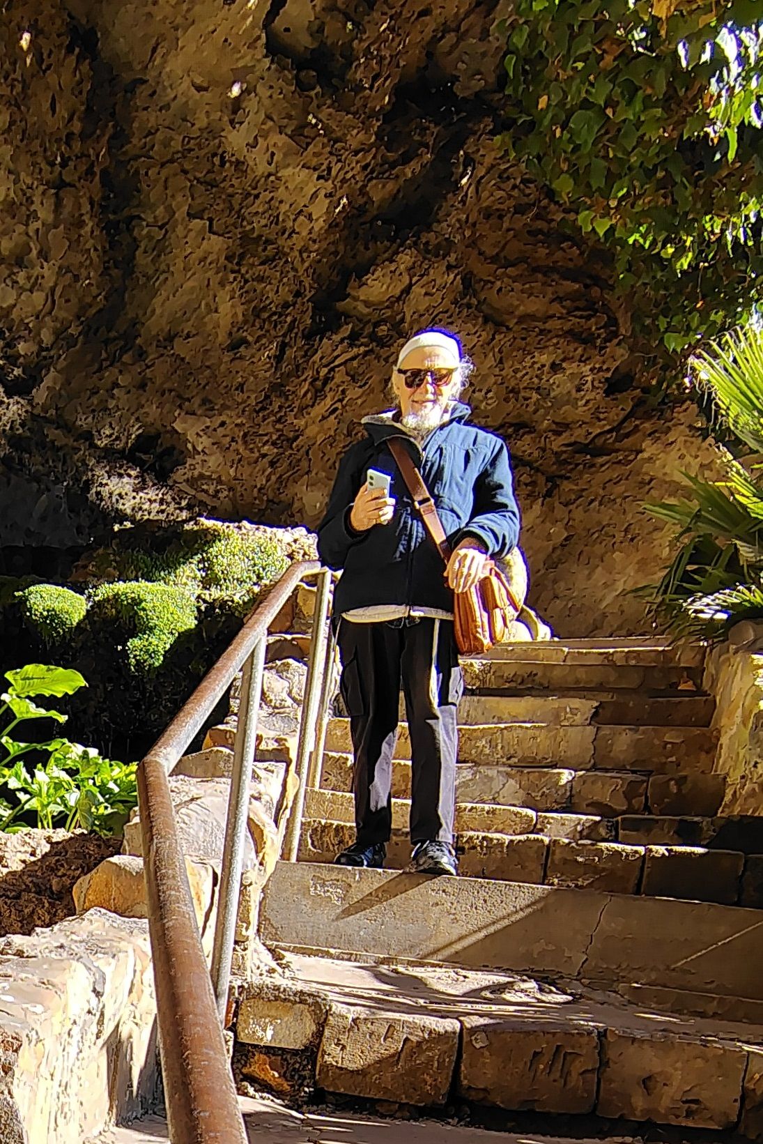 Laurence poses for a photo in front of a rock formation and stairs along a bushwalk. 