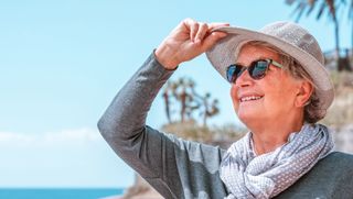 Smiling person on beach wearing hat and sunglasses
