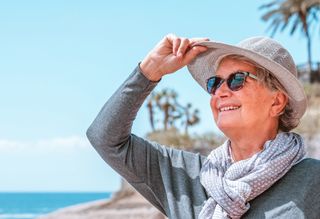 Smiling person on beach wearing hat and sunglasses