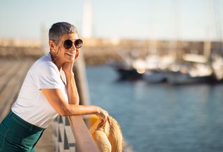 Person standing on marina wearing sunglasses looking out at the water