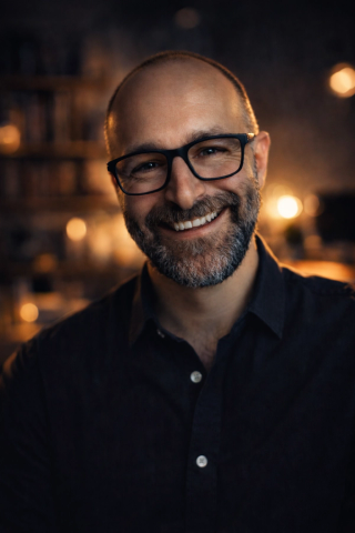 Pascal smiling in front of an orange and black background.