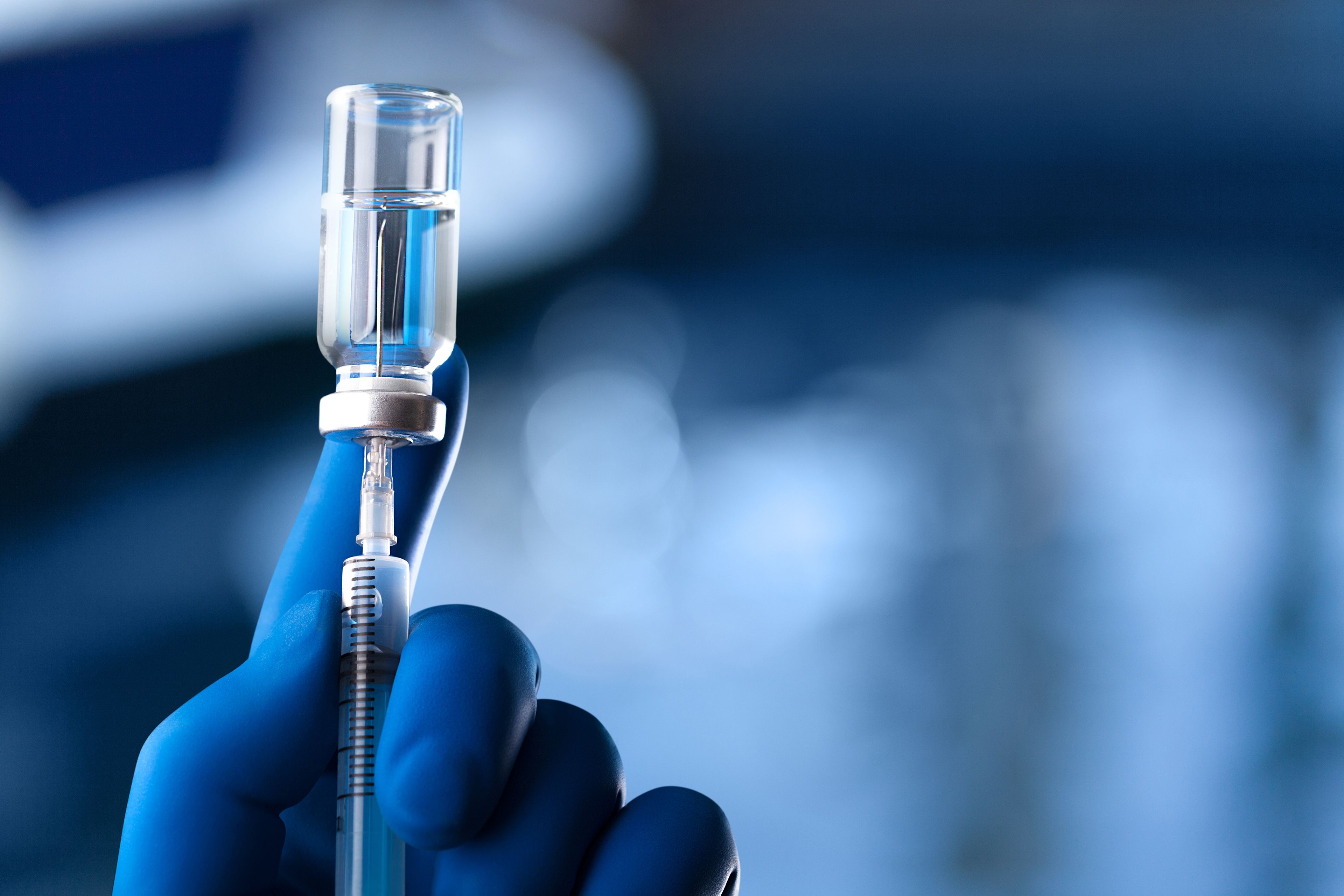Blue gloved hand holding a syringe