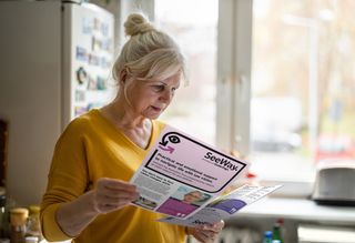 A woman reading two different SeeWay flyers.