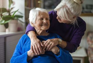 Daughter hugging smiling older mother