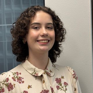 Molly Rice smiling standing in front of an office window.