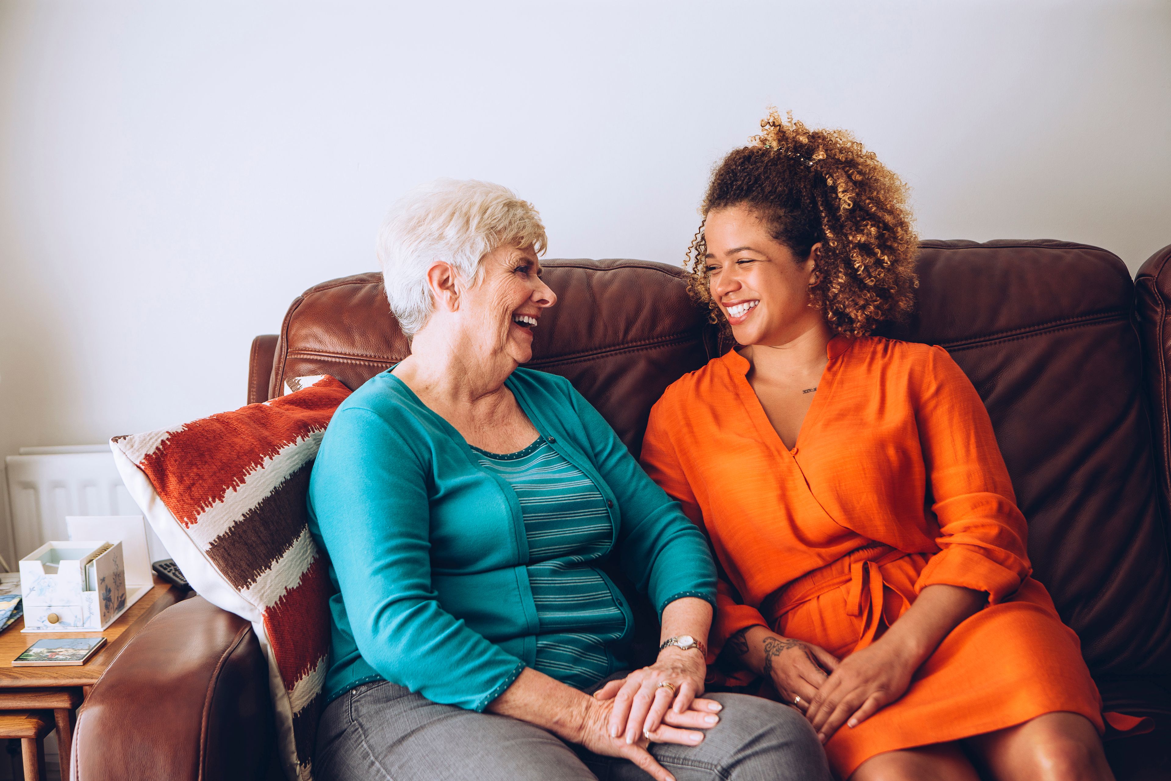 Younger carer laughing with older person on couch