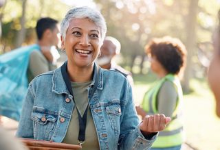 Older woman volunteering in a park with peers in the background