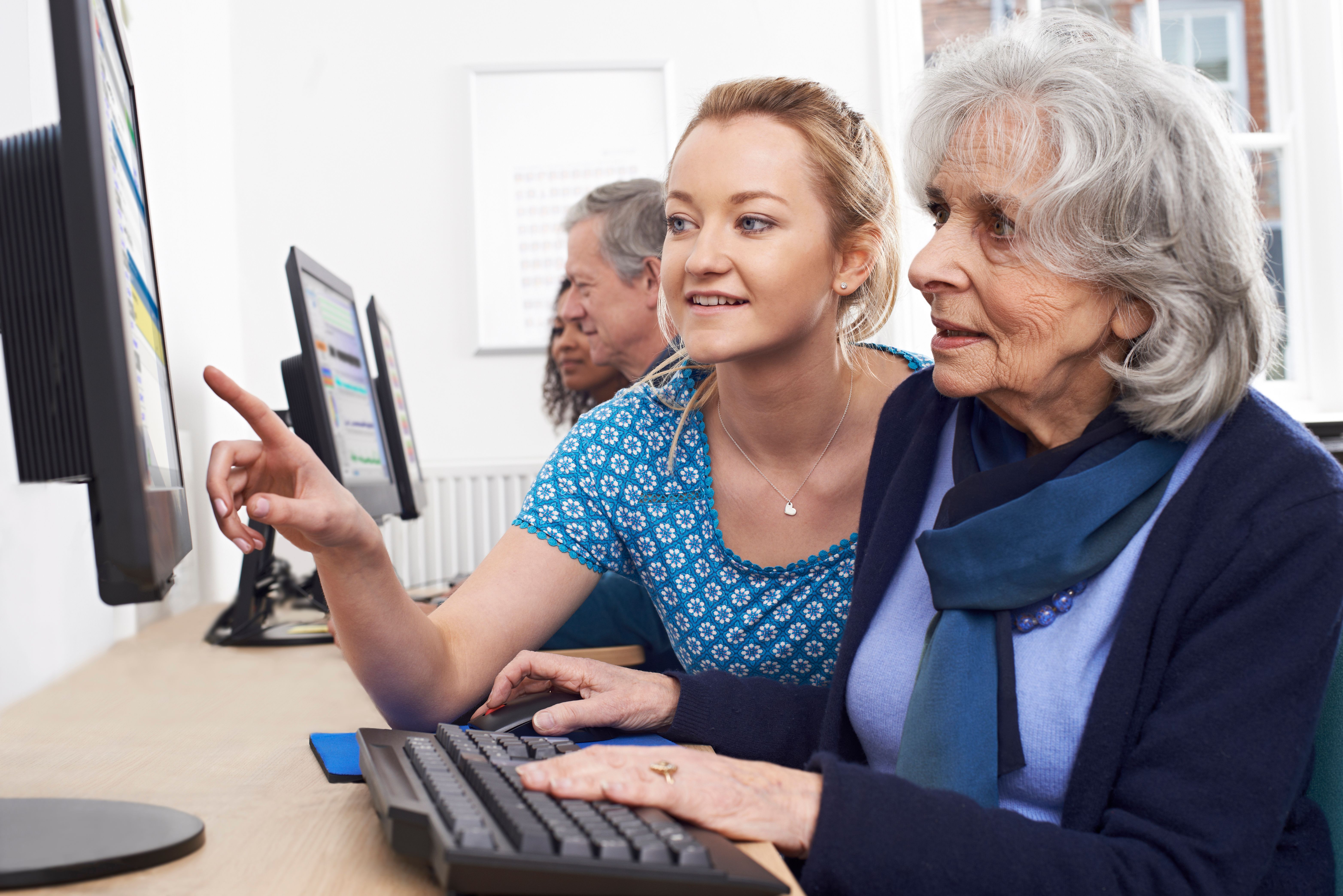 Tutor helping older woman in computer class