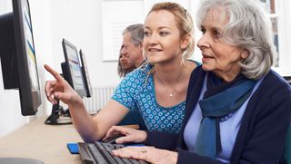 Tutor helping older woman in computer class