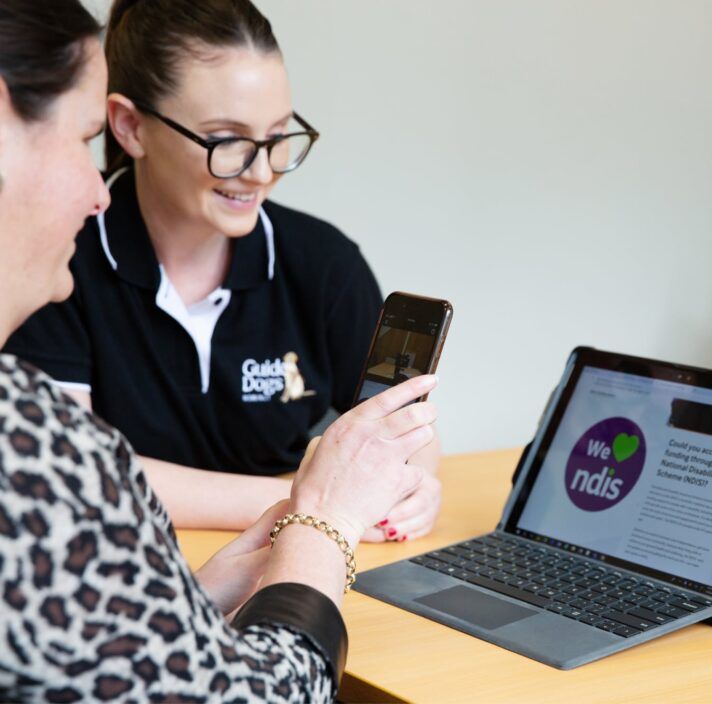 An Assistive Technology specialist works with a Client using their smartphone and a laptop.