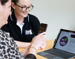 An Assistive Technology specialist works with a Client using their smartphone and a laptop.