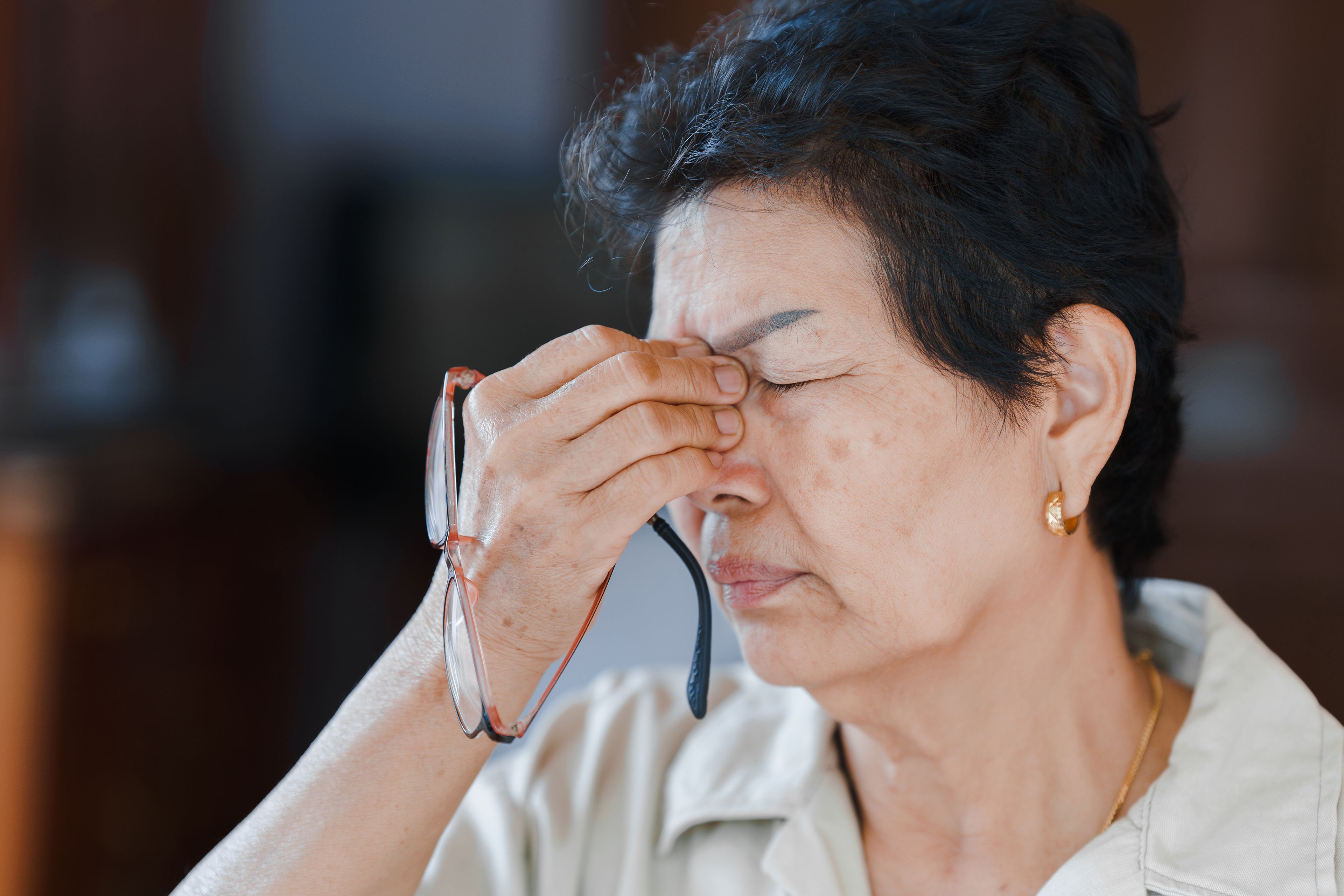 Person pinching nose in discomfort after removing glasses