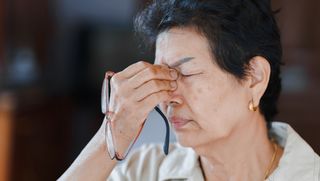 Person pinching nose in discomfort after removing glasses
