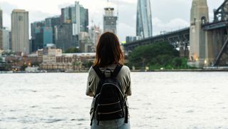 A woman standing with her back to the camera looking at Sydney Harbour