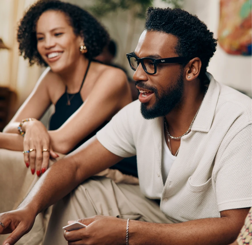Man wearing meta smart glasses talking with a friend on a couch