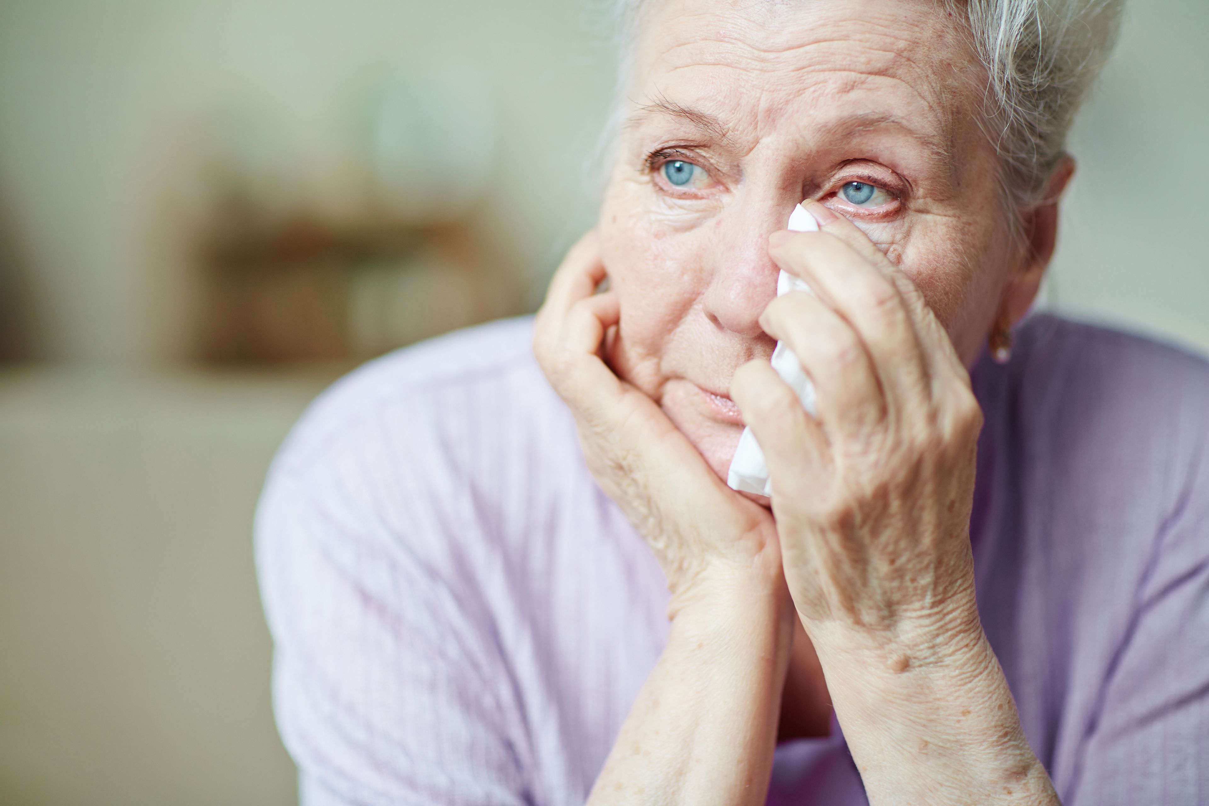 Older person wiping eyes with tissue