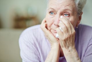 Older person wiping eyes with tissue