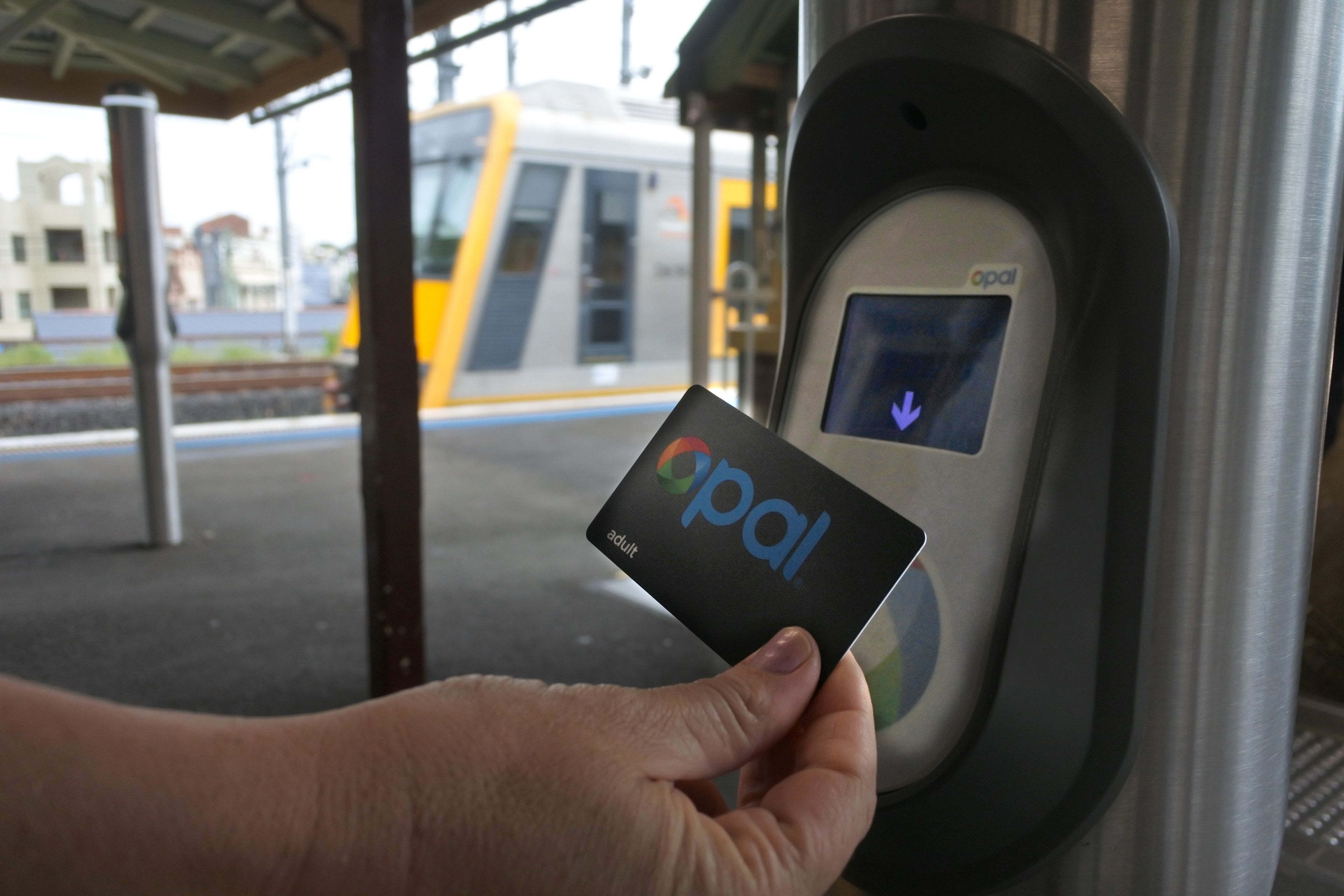 Close up of hand using Opal card at train platform