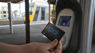 Close up of hand using Opal card at train platform