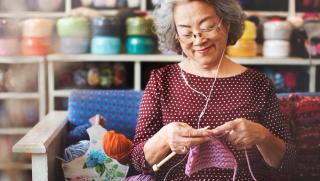 Older person knitting while listening to music using headphones