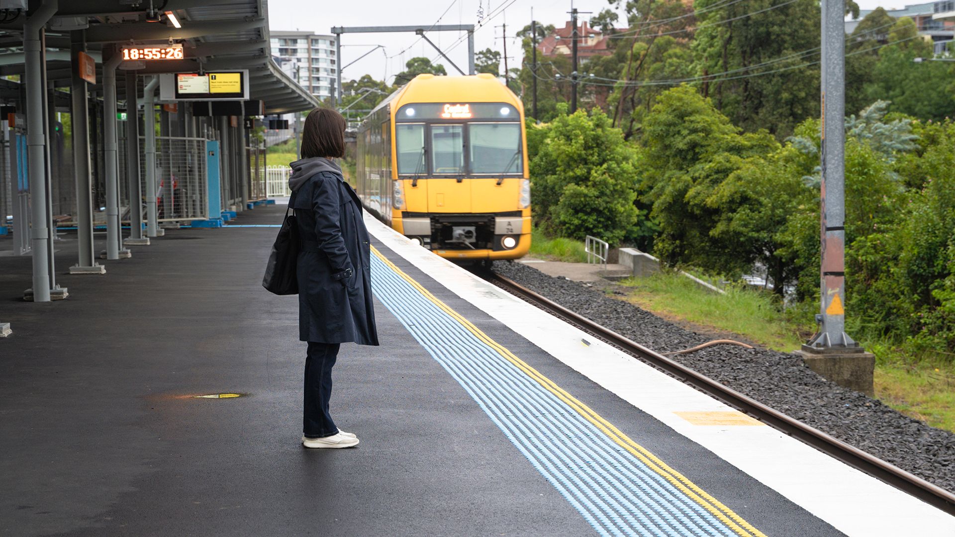 A woman standing on an empty train platform as a train arrives