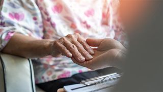 A woman holding her counsellor's hand during a session.